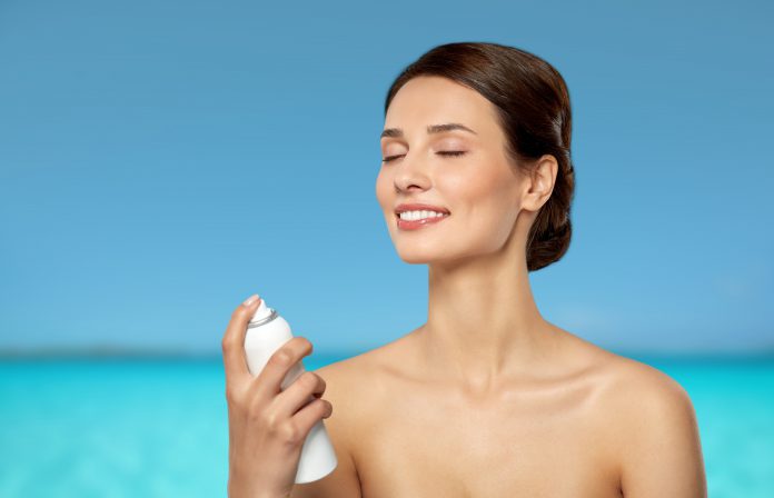 beautiful young woman with facial spray or mist